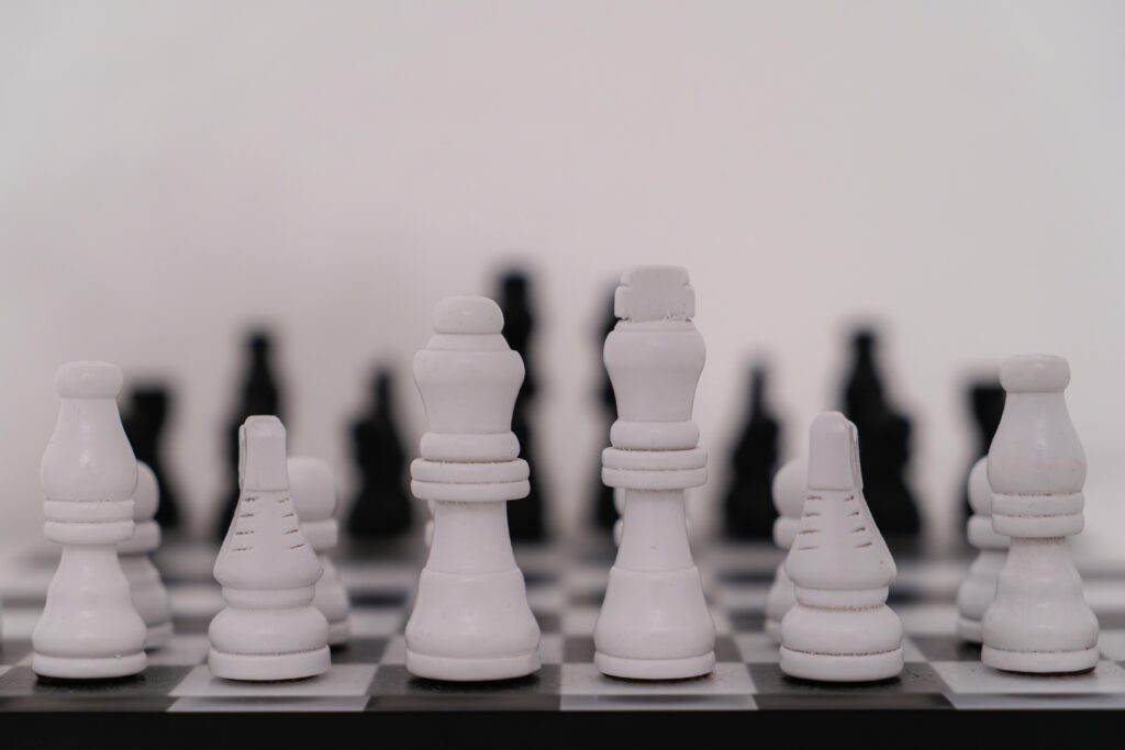 Close-up view of a white chess pieces setup on a board with black pieces in the background.